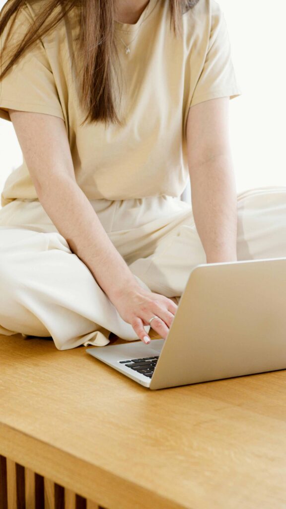 Femme assise en tailleur sur un bureau travaillant sur son laptop - Studio Creajoy webdesigner Versailles